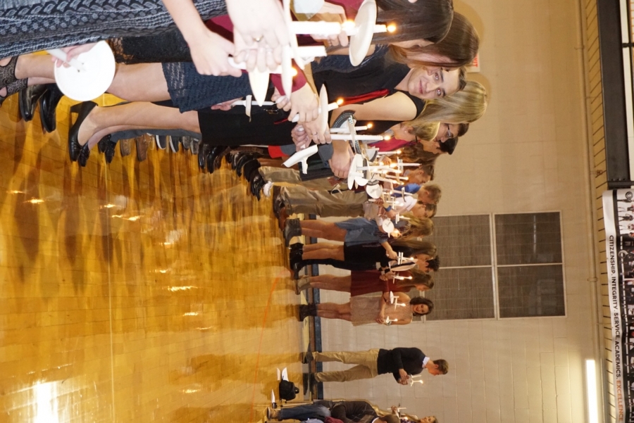 students in a line holding candles